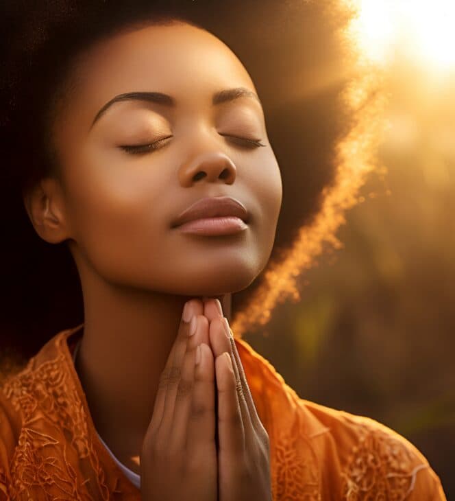 Serene woman meditating outdoors at sunrise, eyes closed and hands in prayer position.
